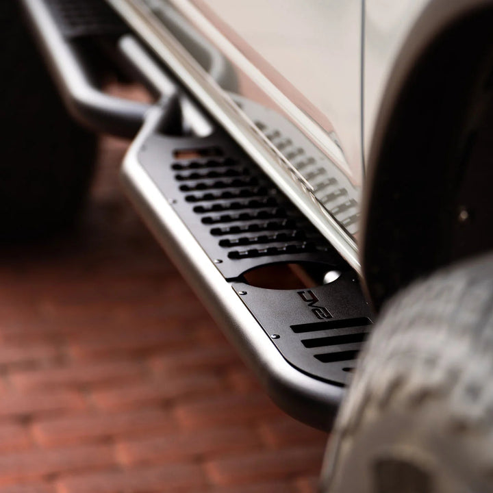 Close-up of a vehicle's side step bar on a brick surface