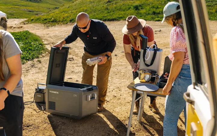 People setting up a camp kitchen and fridge at a trailhead