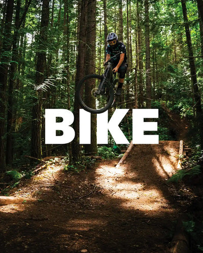 Person riding a bike on a trail in a forest with the word 'BIKE' displayed.