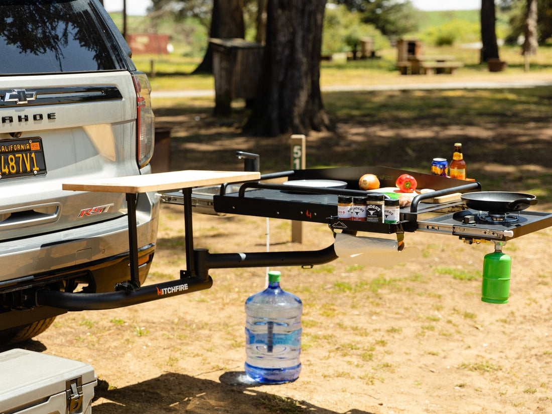 Outdoor setting with a truck tailgate extension featuring a portable stove and cooking items.
