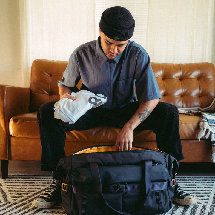 Dometic Unrestricted Duffel soft cooler being packed on a leather couch