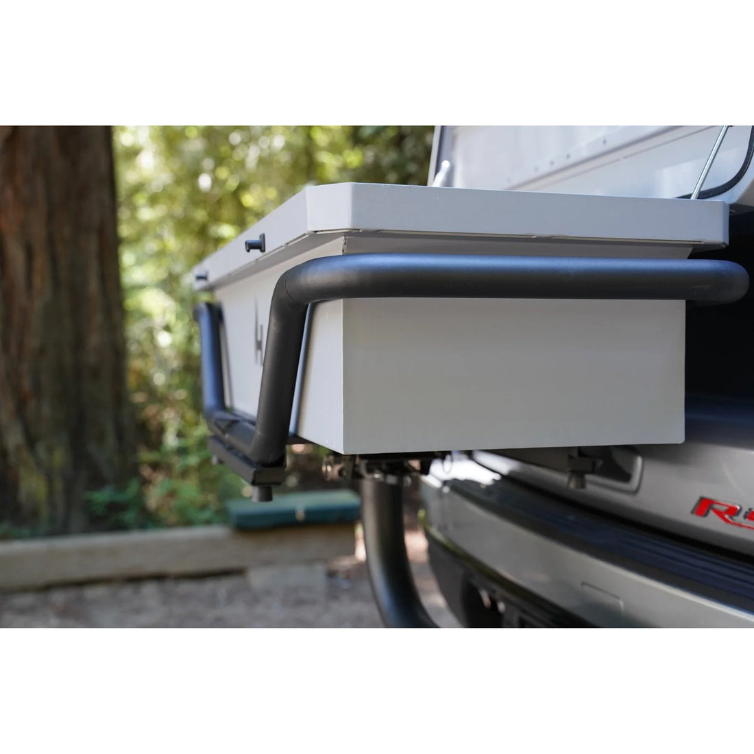 Back of a vehicle with a roof rack and storage box, outdoors.