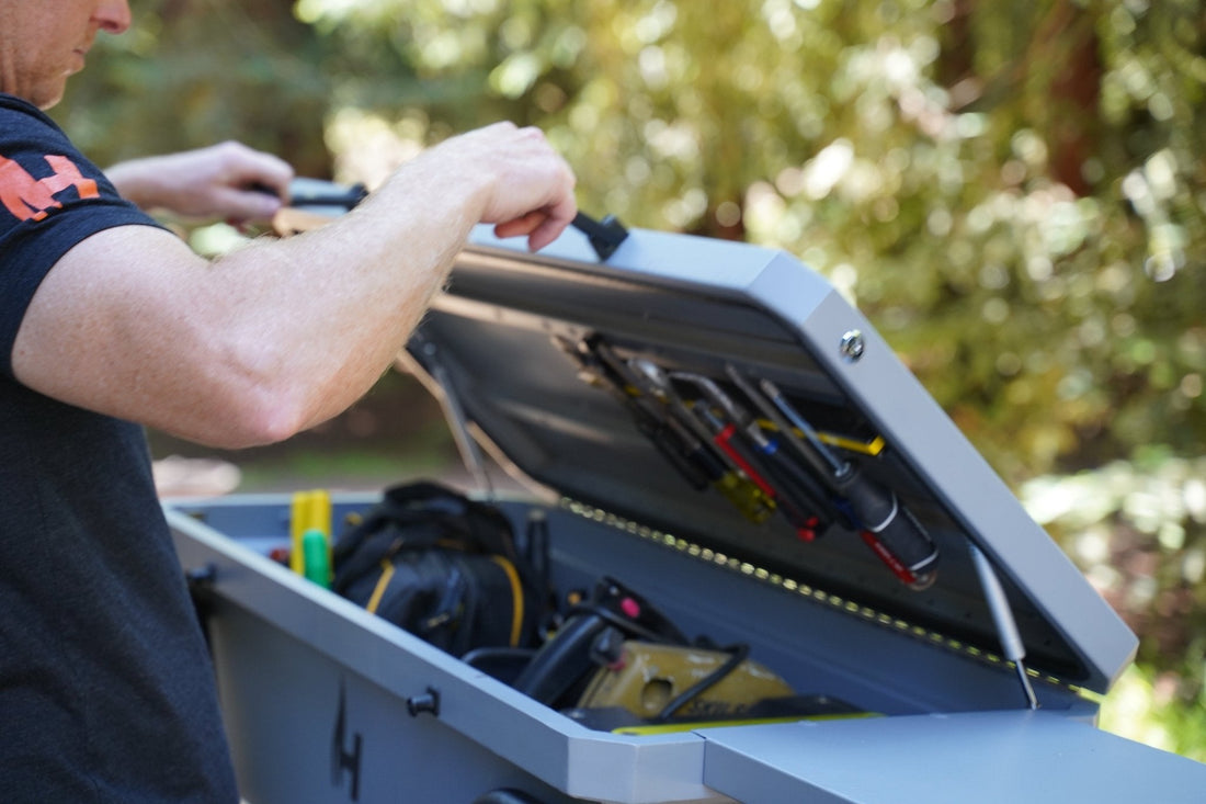 Person opening a tool box with tools inside, outdoors.