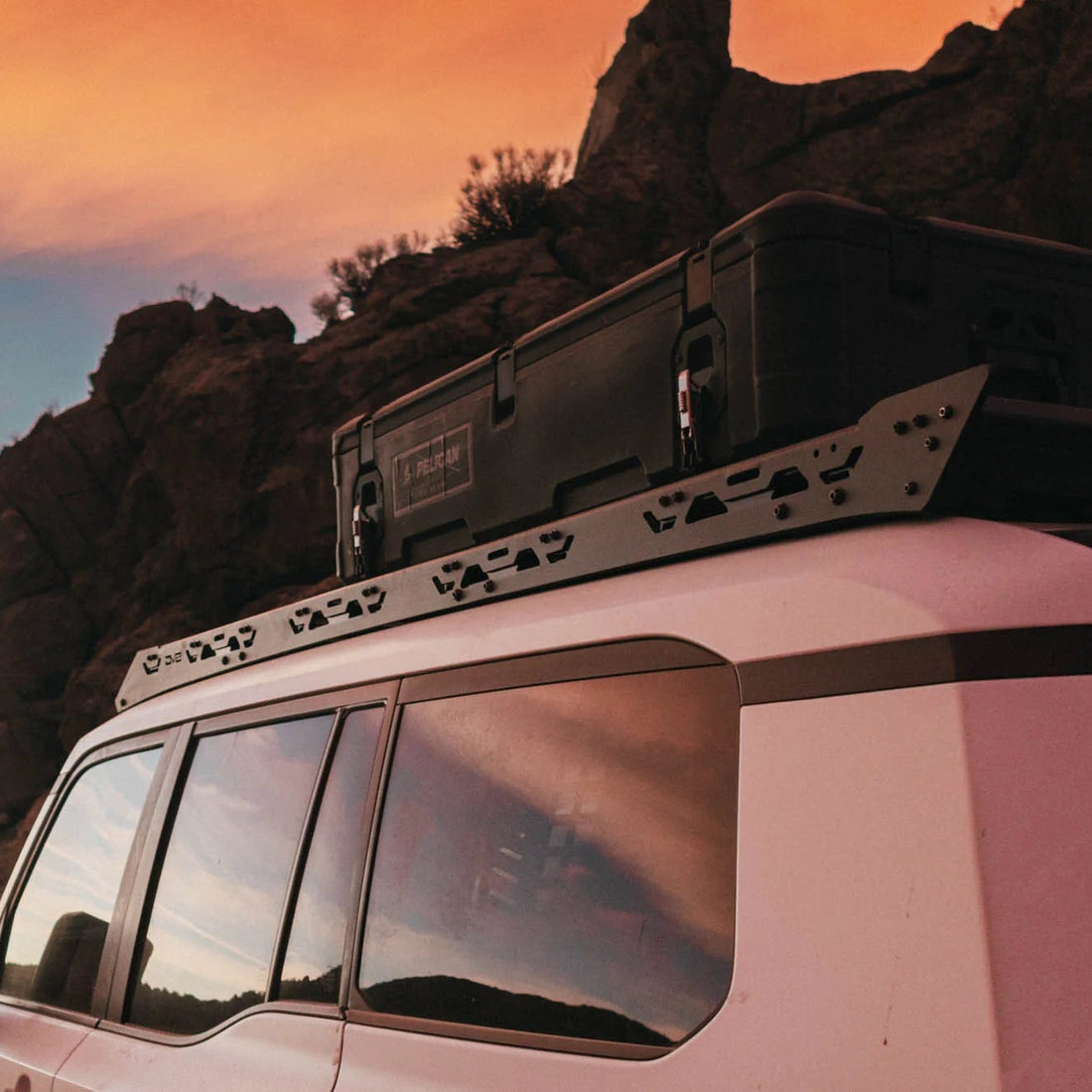 Land Cruiser with roof rack on a rocky landscape during sunset