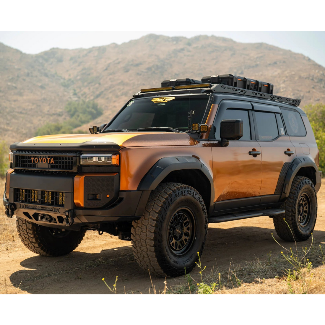 Toyota SUV with off-road equipment on a dirt road with mountains in the background