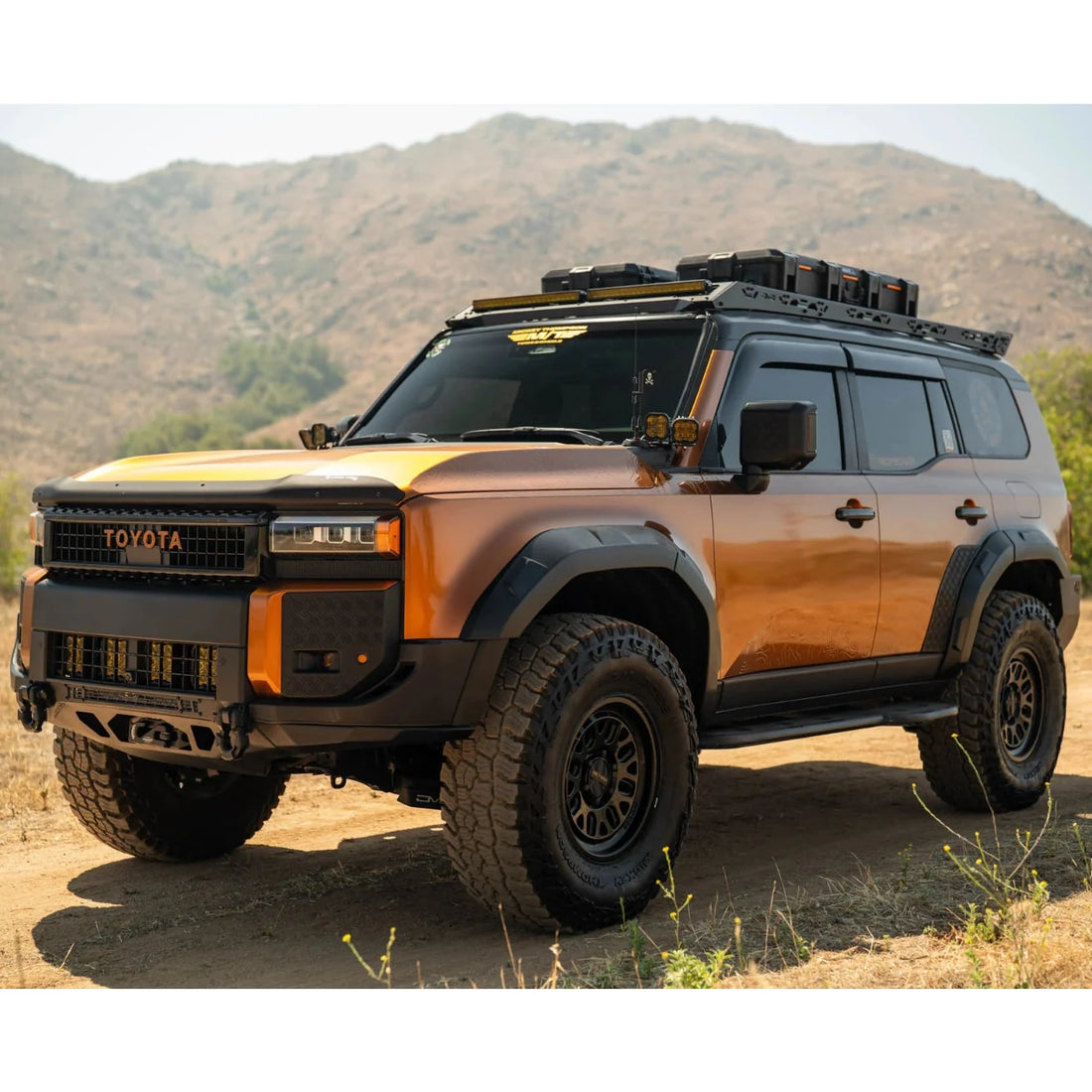 Toyota SUV with off-road equipment on a dirt road with mountains in the background