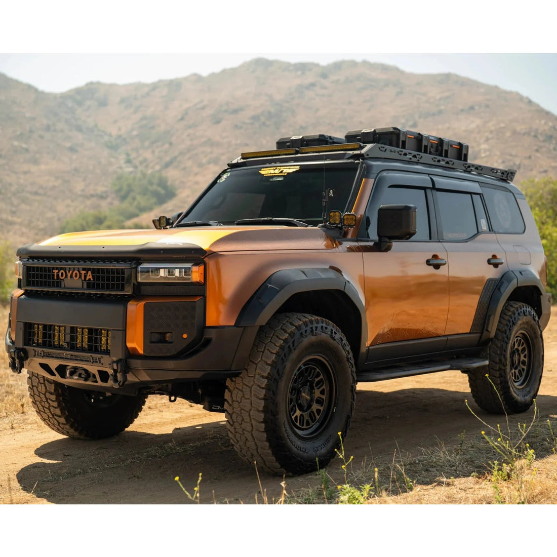 Toyota SUV with off-road equipment on a dirt road with mountains in the background
