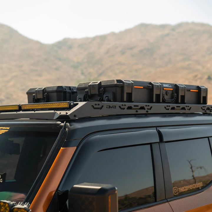 SUV with roof rack and off-road lights against a mountainous landscape