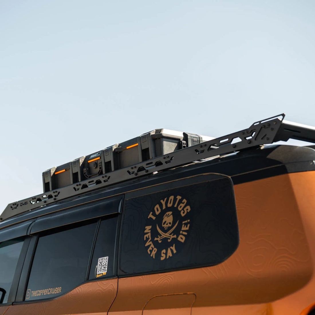 Orange Toyota vehicle with a roof rack against a clear sky