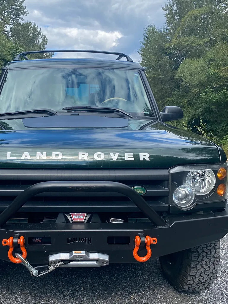 Green Land Rover Discovery II with a winch bumper and roof rack