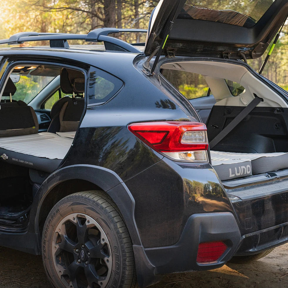Side view of a Subaru Crosstrek with the rear door open showing the Luno AIR+FOAM Pro mattress