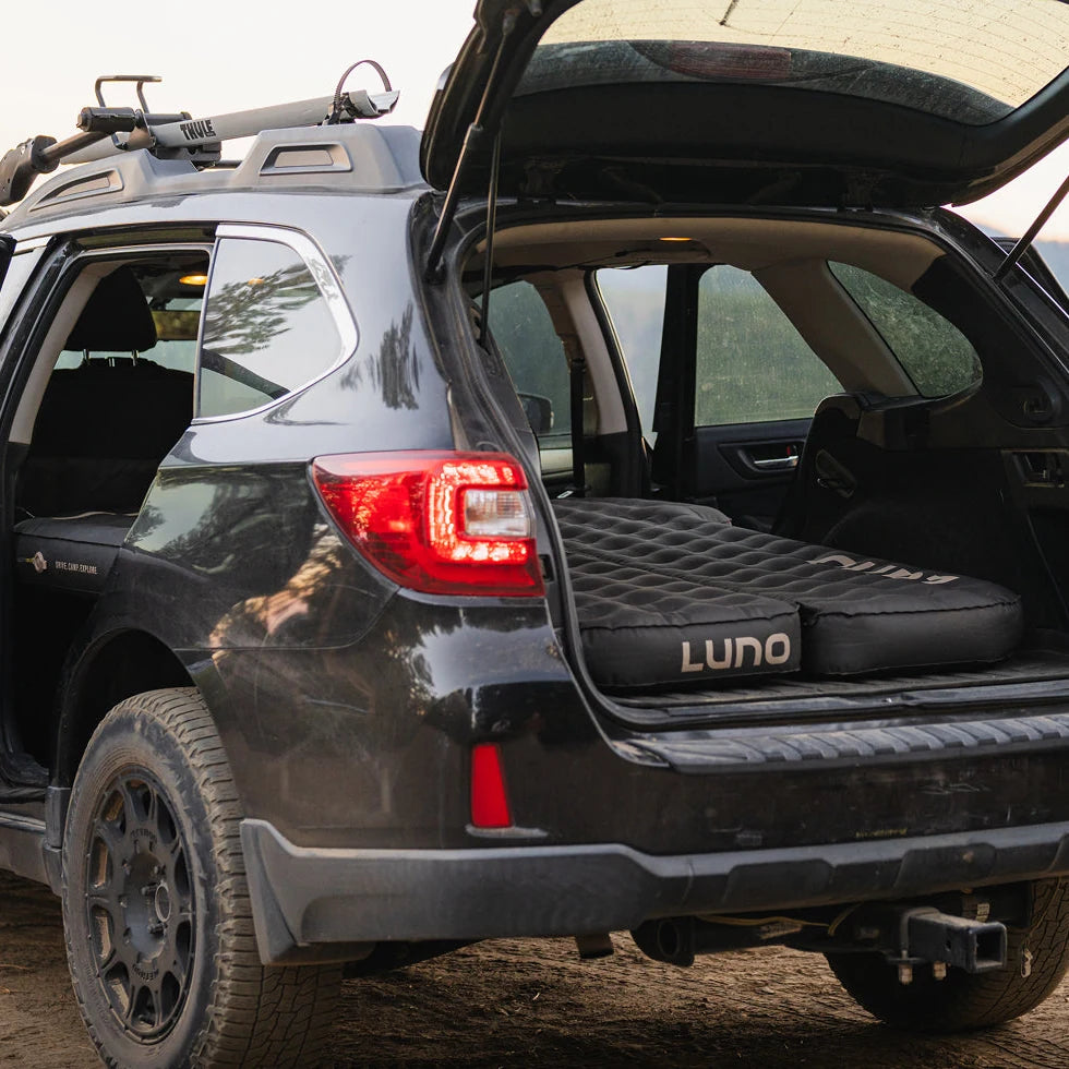 Side view of a Subaru Outback with the rear hatch open showing the Luno AIR Pro mattress