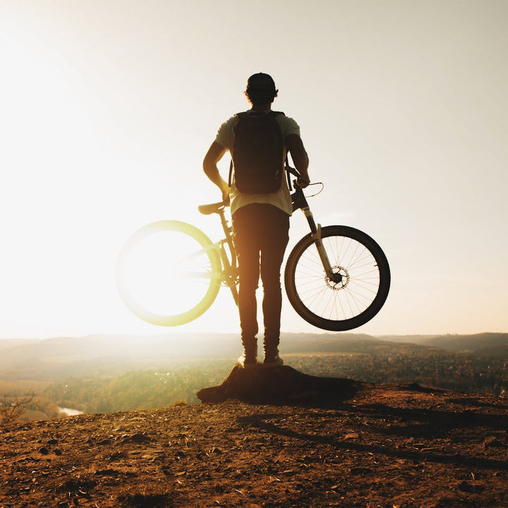 Mountain biker standing with bike at sunset