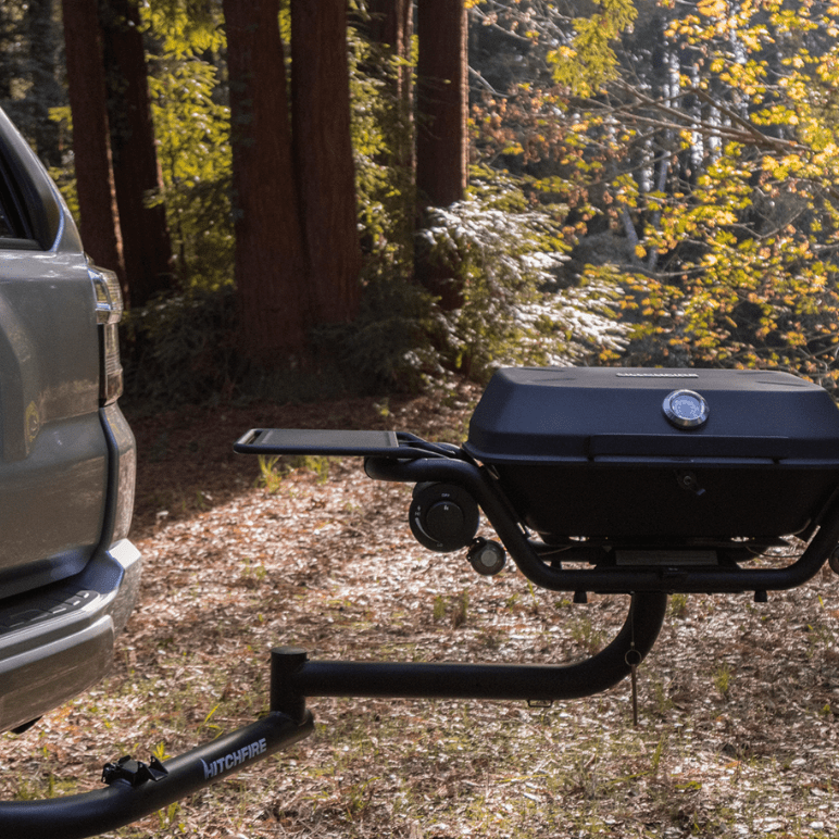 Portable grill attached to a vehicle in a forest setting