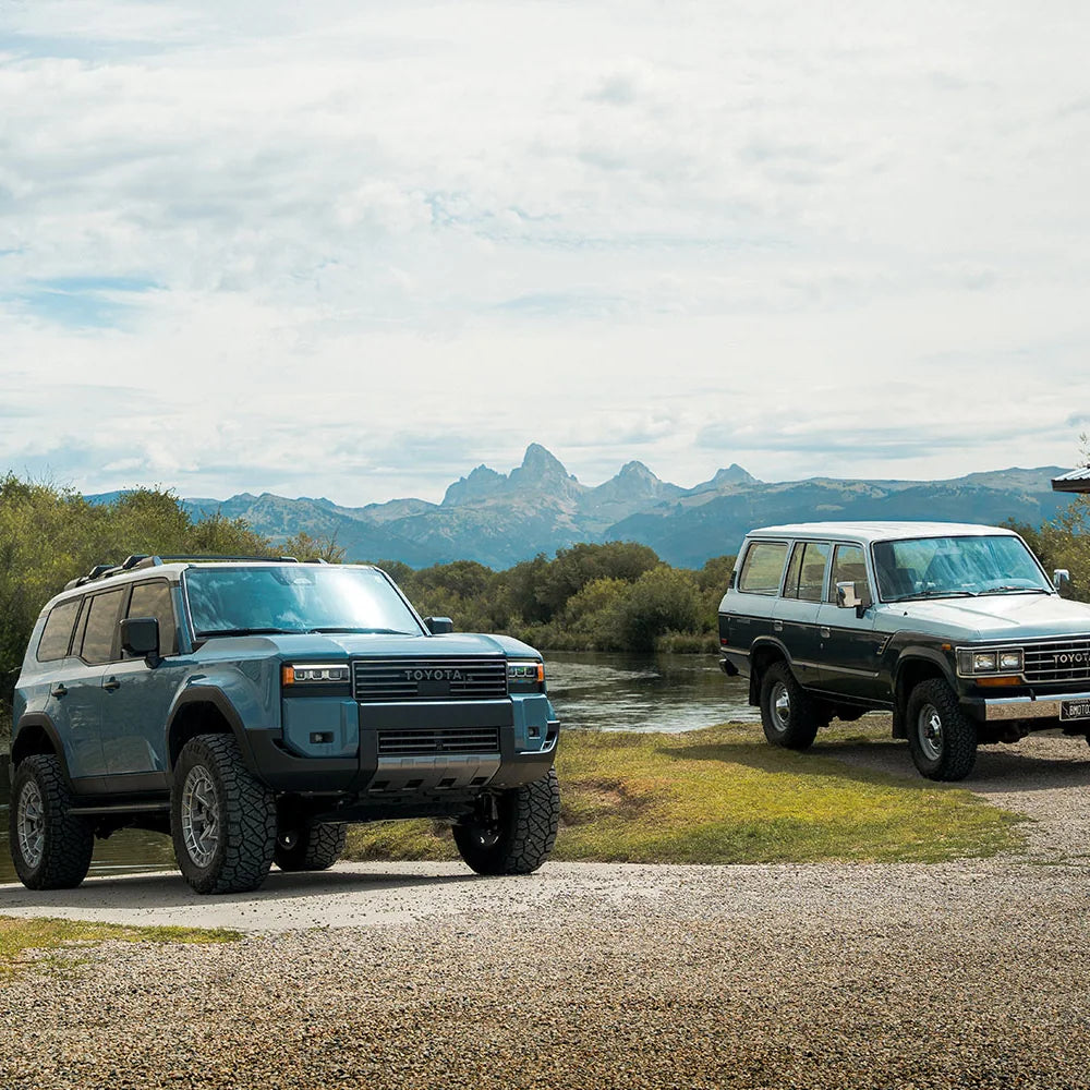 Two Land Cruisers parked on a hill, one with the CBI Heritage grille