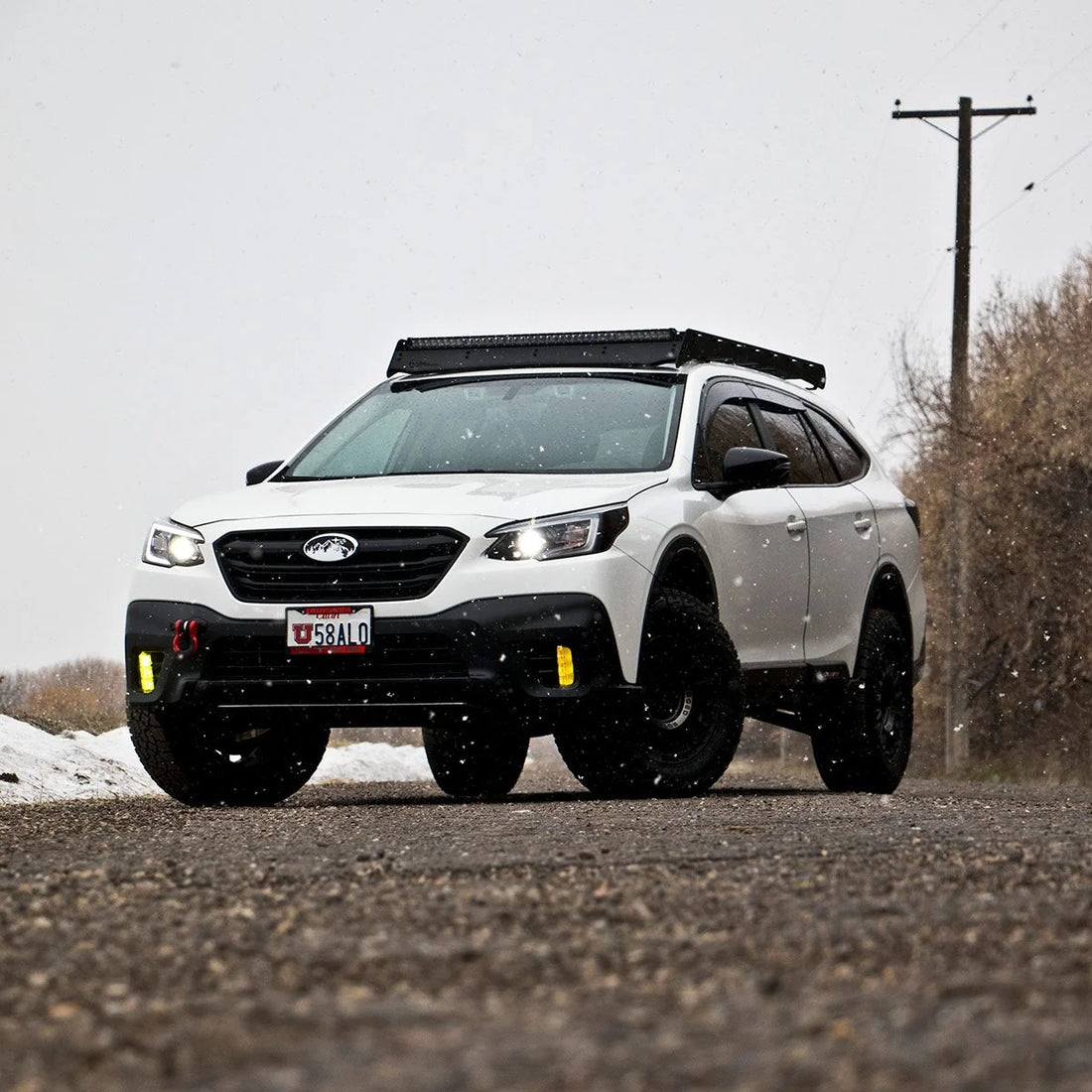 Subaru Outback with Prinsu roof rack, front three-quarter view on a gravel road