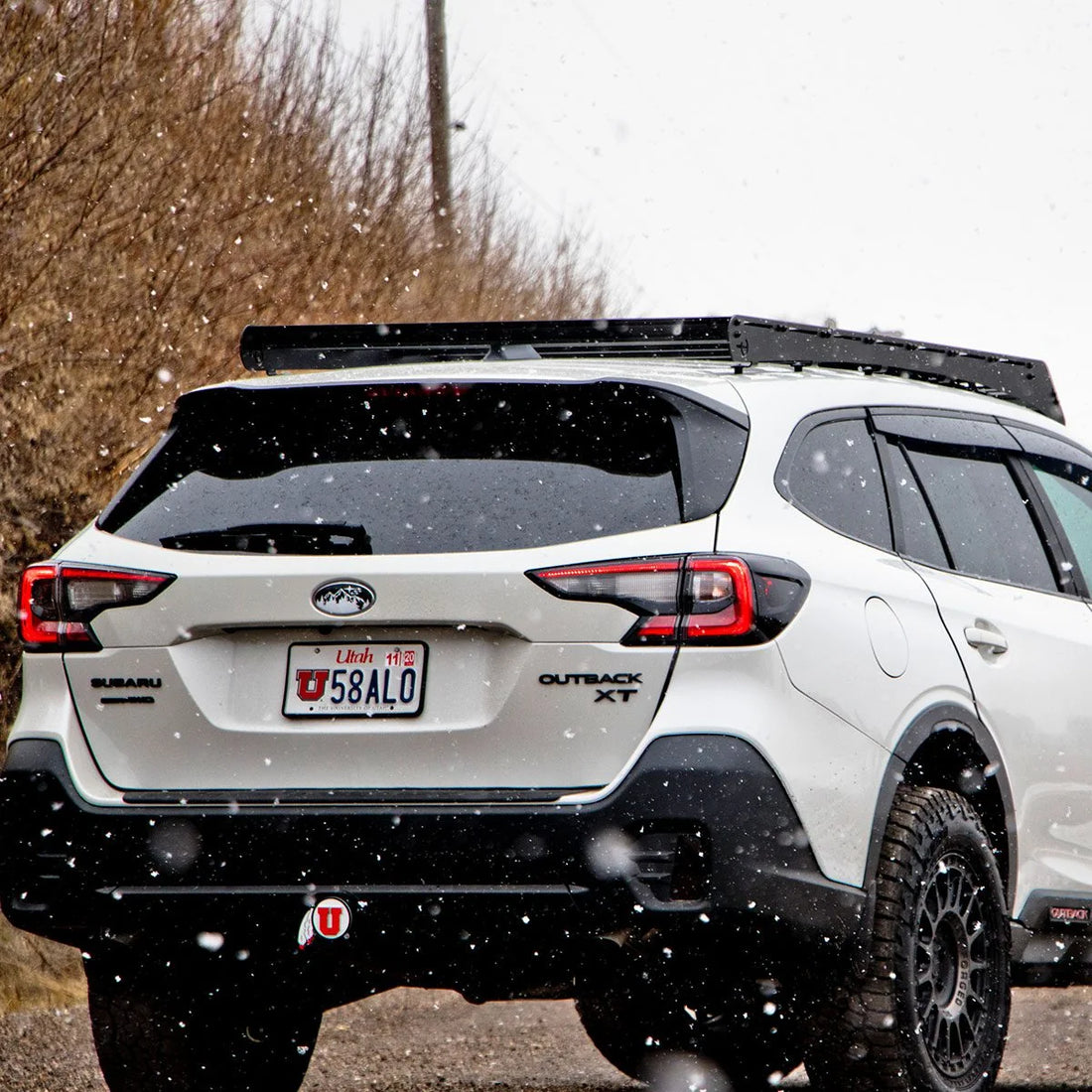 Rear view of a 6th Gen Subaru Outback with a Prinsu roof rack in the snow