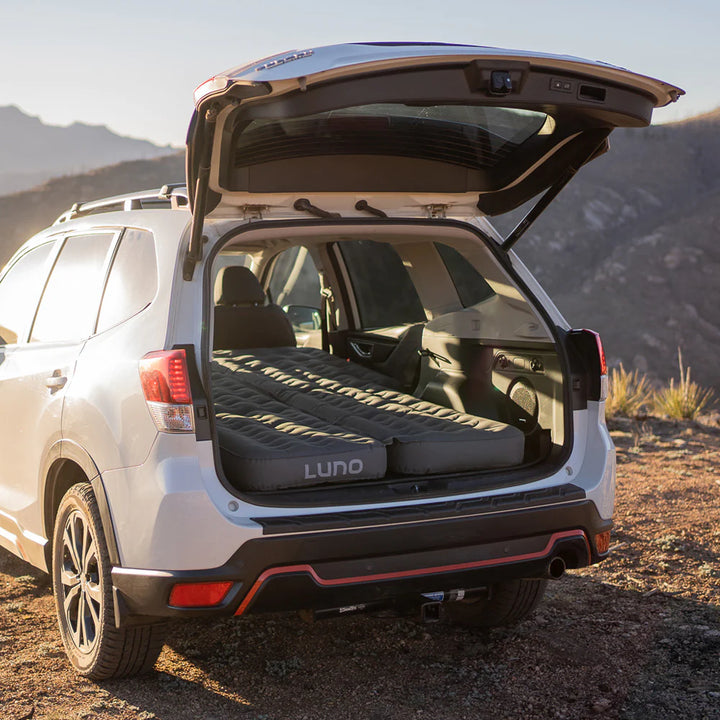 SUV with rear hatch open showing Luno inflatable car camping mattress setup outdoors